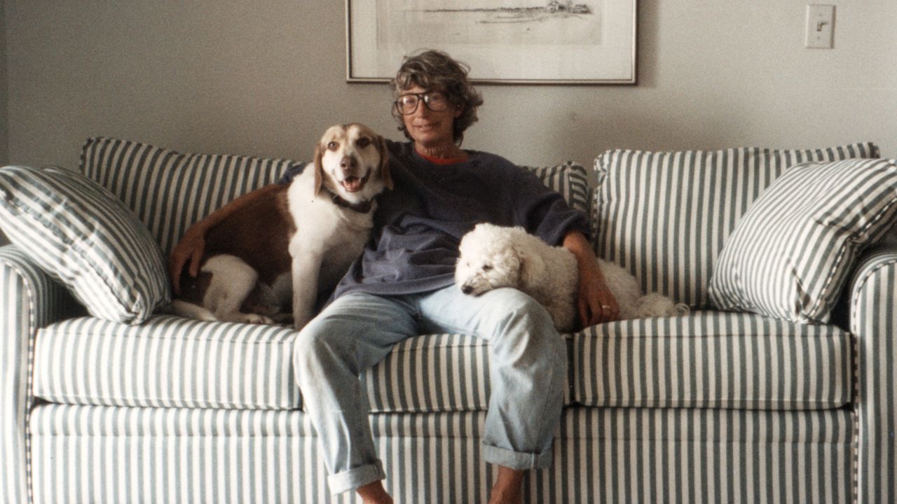a woman with glasses and two dogs on a sofa